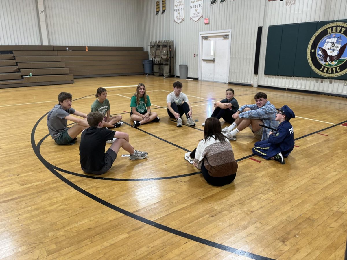 Best Buddies leaders sit in a circle with their FC buddies in the NJROTC gym for their Halloween party.