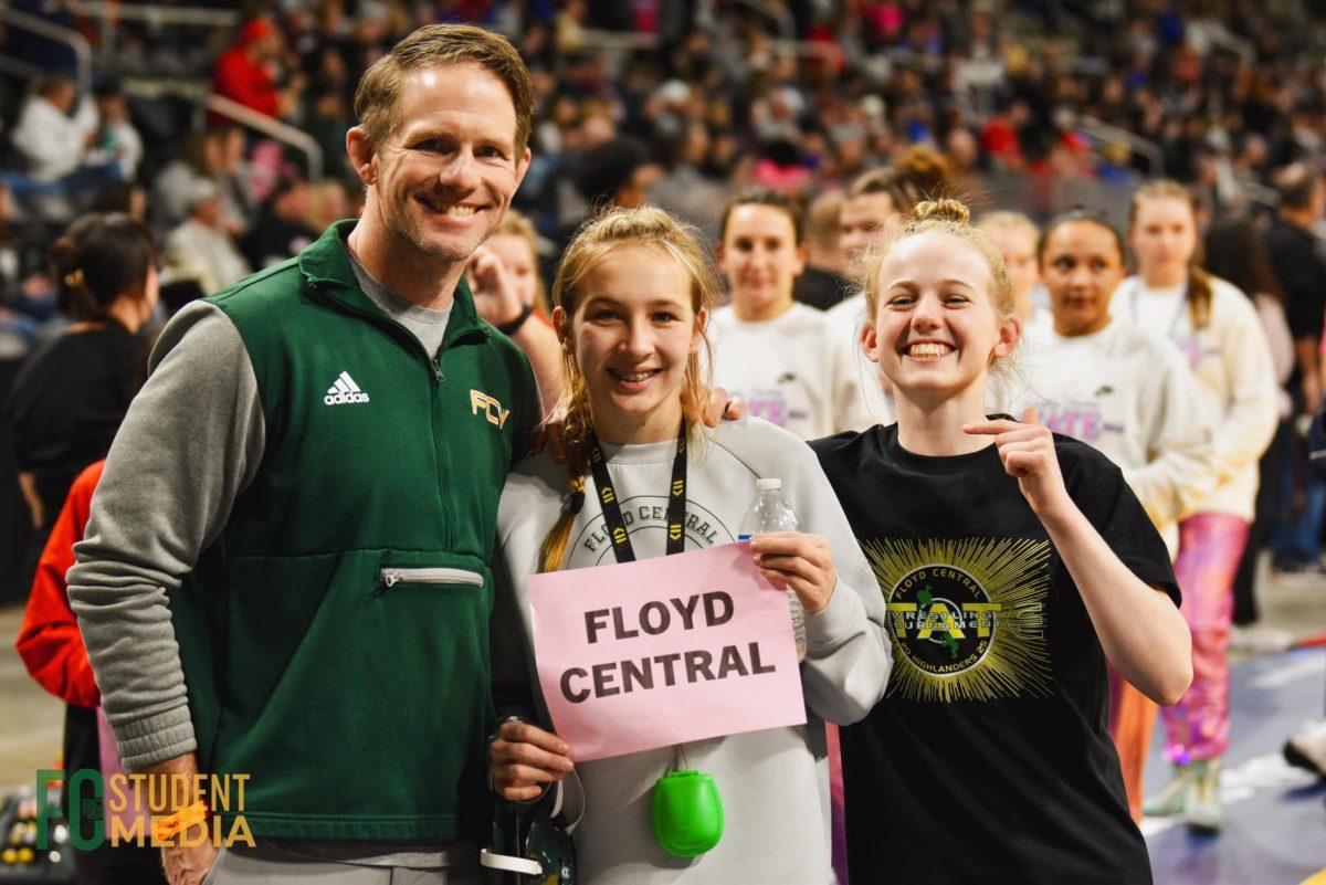 Wrestling coach Brandon Sisson, freshman Scarlette Rudnick, and Addalyn Sisson pose for a photo during the Parade of Champions before the girls state wrestling finals meet begins. 