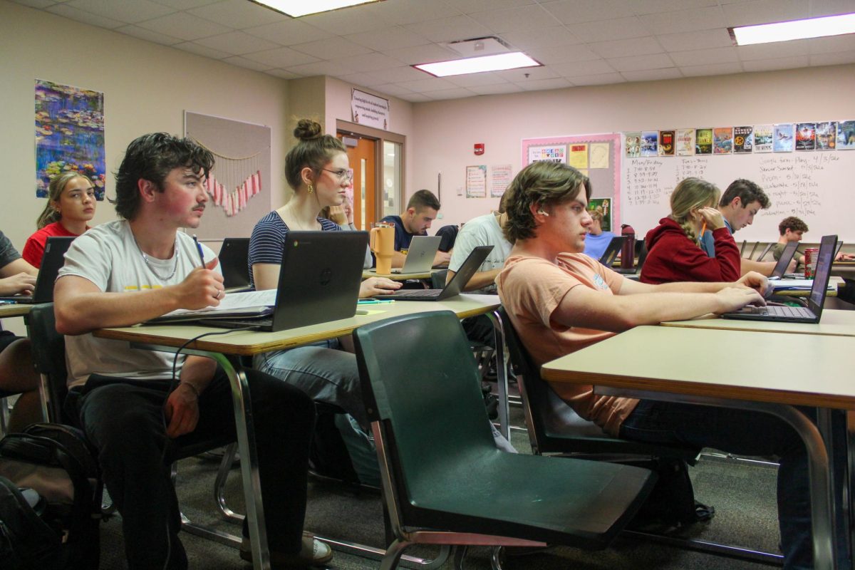 Seniors William Scott, Clara Cain, and Isaac Taylor take notes in their English 12 Honors class.