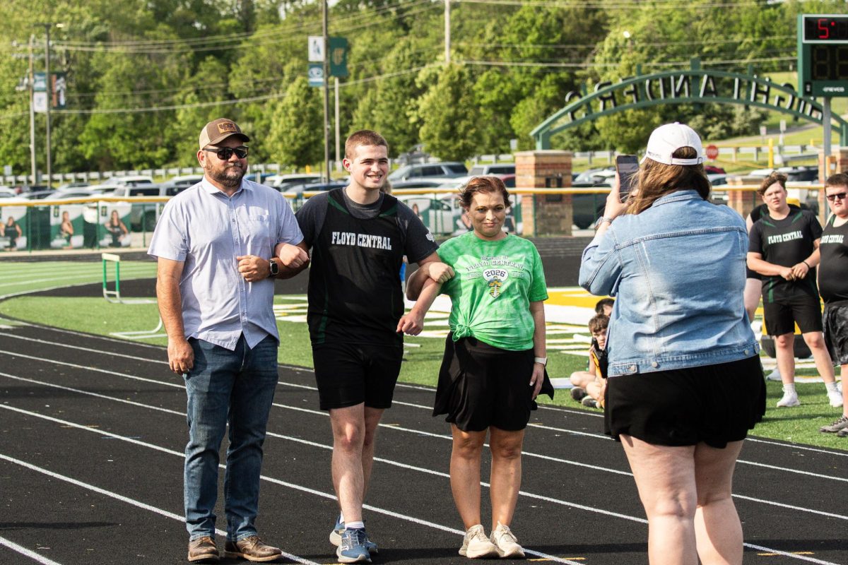 Senior Zach King walks out with his parents on Senior Night for unified track.